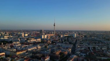Berlin TV kulesi şehrin üzerinde dikiliyor, altın saatin sıcacık parıltısıyla yıkanıyor. uçuş üstü insansız hava aracı 
