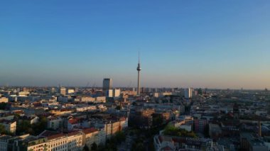 Berlin TV kulesi şehrin üzerinde dikiliyor, altın saatin sıcacık parıltısıyla yıkanıyor. İHA yükseliyor 