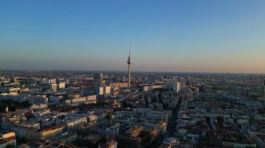 Berlin TV kulesi şehrin üzerinde dikiliyor, altın saatin sıcacık parıltısıyla yıkanıyor. panorama genel görünüm dronu 