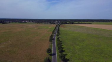 Ağaçlar ve tarlalarla dolu kırsal bir araziden geçen boş bir asfalt yolun havadan görünüşü. hız rampası hiper hareket zaman aşımı 