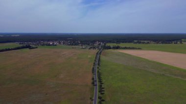 Ağaçlar ve tarlalarla dolu kırsal bir araziden geçen boş bir asfalt yolun havadan görünüşü. uçuş üstü insansız hava aracı 