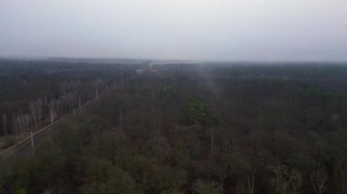 Demiryolu manzarası bulutlu gökyüzü altındaki büyük ormanı geçerek karamsar ve atmosferik manzaralar yaratıyor. Dolly sol İHA 