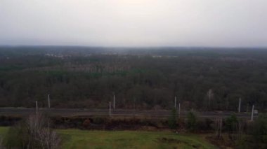 Demiryolu manzarası bulutlu gökyüzü altındaki büyük ormanı geçerek karamsar ve atmosferik manzaralar yaratıyor. uçuş üstü insansız hava aracı 