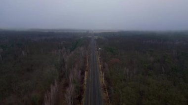 Demiryolu manzarası bulutlu gökyüzü altındaki büyük ormanı geçerek karamsar ve atmosferik manzaralar yaratıyor. Ters İHA uçuşu 