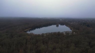 Göle bakan, ağaçlarla çevrili ve Almanya 'da bulutlu bir gökyüzünü yansıtan insansız hava aracı. uçuş üstü insansız hava aracı 