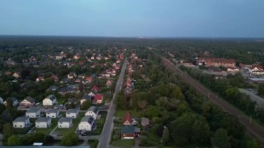 Alacakaranlıkta küçük bir köy ve ormandan geçen tren, hava manzaralı. doly sağ drone 