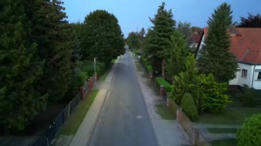 Brandenburg, Almanya 'da sakin bir akşam, çatıların, yemyeşil otlakların ve bir yol ağının sergilendiği bir yerleşim alanına iniyor. Ters İHA uçuşu 
