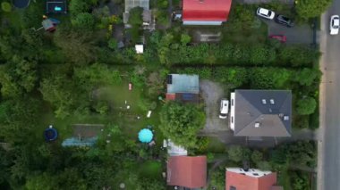 Brandenburg, Almanya 'da sakin bir akşam, çatıların, yemyeşil otlakların ve bir yol ağının sergilendiği bir yerleşim alanına iniyor. dikey kuş bakışı dron 