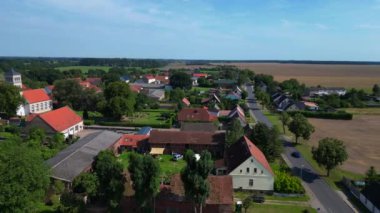 Almanya 'nın Brandenburg kentinde güneşli bir yaz gününde geniş tarım sahalarının ortasına kurulmuş küçük bir köy olan Tarmow' un Idyllic manzarası. Ters İHA uçuşu 