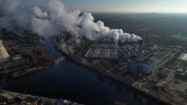 Endüstriyel bacalar mavi gökyüzünün altında beyaz duman yayıyor, kirlilik kavramı. Yukarıdan aşağıya doğru uçur 