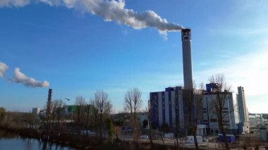 Güneşli bir günde şehrin üzerine büyük miktarlarda duman salan büyük bir sanayi enerji santralinin havadan görüntüsü. İHA alçalıyor 
