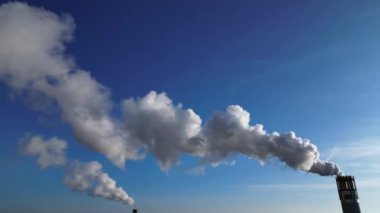 Endüstriyel bacalar mavi gökyüzünün altında beyaz duman yayıyor, kirlilik kavramı. statik üç ayaklı insansız hava aracı 