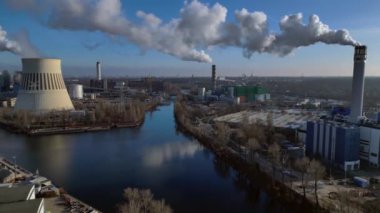 Nehir kenarındaki soğutma kulesinden buhar çıkaran ve şehir manzarasına bakan bir enerji santralinin hava görüntüsü. uçuş üstü insansız hava aracı 