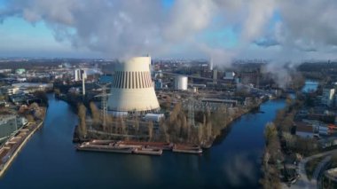 Güneşli bir günde, arka planda bir nehir ve şehir bulunan bir termik santralin dumanı yayan hava görüntüsü. hız rampası hiper hareket zaman aşımı 