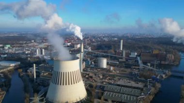 Güneşli bir günde, arka planda bir nehir ve şehir bulunan bir termik santralin dumanı yayan hava görüntüsü. statik üç ayaklı insansız hava aracı 