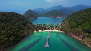 Koh Changs, yemyeşil yemyeşil, el değmemiş bir plaj ve turkuaz sulara uzanan sakin bir rıhtım manzarası içerir. panorama genel görünüm dronu 