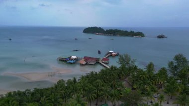 Koh Rong adası, bereketli palmiye ağaçları, canlı turkuaz suları ve geleneksel stilt evleriyle tropikal cennetin özünü yakalıyor. statik üç ayaklı insansız hava aracı 