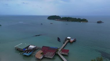 Koh Rong adası, bereketli palmiye ağaçları, canlı turkuaz suları ve geleneksel stilt evleriyle tropikal cennetin özünü yakalıyor. İHA alçalıyor 