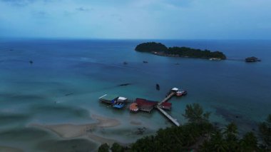 Koh Rong adası, bereketli palmiye ağaçları, canlı turkuaz suları ve geleneksel stilt evleriyle tropikal cennetin özünü yakalıyor. panorama genel görünüm dronu 