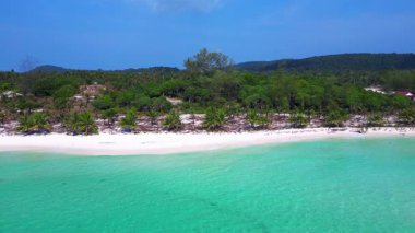 Beyaz kumu yıkayan turkuaz suyla Sok San Sahili 'nin havadan görünüşü. Palmiye ağaçları ve tropikal bitki örtüsüyle çevrili. doly sağ drone 