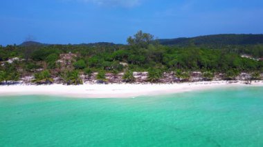 Beyaz kumu yıkayan turkuaz suyla Sok San Sahili 'nin havadan görünüşü. Palmiye ağaçları ve tropikal bitki örtüsüyle çevrili. panorama genel görünüm dronu 