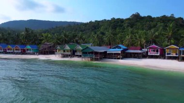 Kamboçya 'daki Koh Rong adasındaki tropik bir plajda yükselen renkli bungalovların hava manzarası. statik üç ayaklı insansız hava aracı 