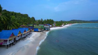 Kamboçya 'daki Koh Rong adasındaki tropik bir plajda yükselen renkli bungalovların hava manzarası. Ters İHA uçuşu 