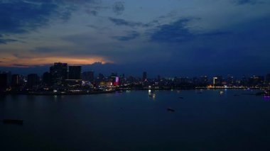 Phnom Penh ufuk çizgisi üzerinde gün batımı aydınlanmış bir köprüyle nehri geçmek ve yüzen tur tekneleriyle. panorama genel görünüm dronu 