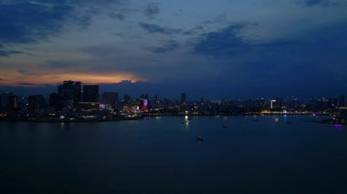 Phnom Penh ufuk çizgisi üzerinde gün batımı aydınlanmış bir köprüyle nehri geçmek ve yüzen tur tekneleriyle. uçuş üstü insansız hava aracı 