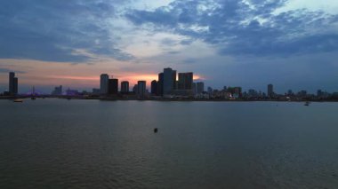 Phnom Penh ufuk çizgisi günbatımında Mekong nehrine renkli bulutlar ve arka planda bir köprüyle yansıyor. uçuş üstü insansız hava aracı 