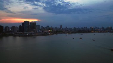 Phnom Penh ufuk çizgisi günbatımında Mekong nehrine renkli bulutlar ve arka planda bir köprüyle yansıyor. Sol İHA 'ya dön 