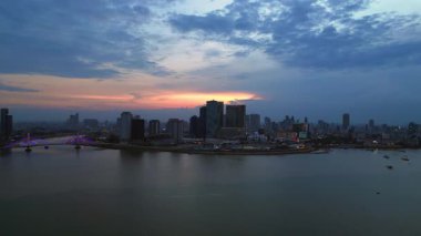 Phnom Penh ufuk çizgisi günbatımında Mekong nehrine renkli bulutlar ve arka planda bir köprüyle yansıyor. panorama genel görünüm dronu 
