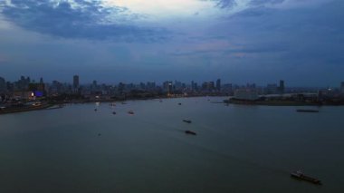 Phnom Penh ufuk çizgisi günbatımında Mekong nehrine renkli bulutlar ve arka planda bir köprüyle yansıyor. Sol İHA 'ya dön 