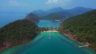 Koh Changs, yemyeşil yemyeşil, el değmemiş bir plaj ve turkuaz sulara uzanan sakin bir rıhtım manzarası içerir. panorama genel görünüm dronu 