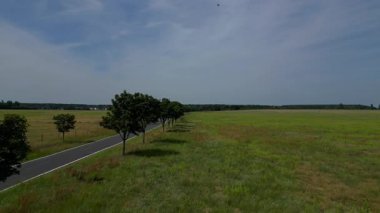 Yol, ağaçlar ve ekilmiş tarlaları olan kırsal bir arazinin havadan görünüşü. Ters İHA uçuşu 