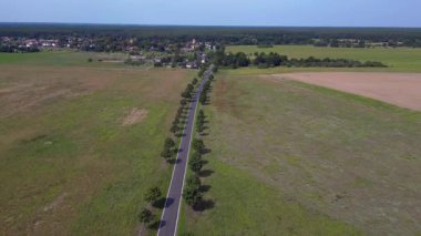 Ağaçlar ve tarlalarla dolu kırsal bir araziden geçen boş bir asfalt yolun havadan görünüşü. hız rampası hiper hareket zaman aşımı 