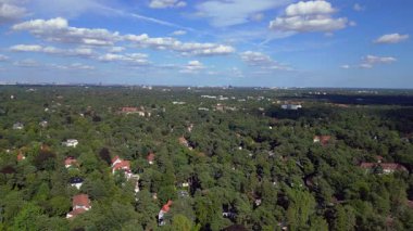 Hayır, Berlin 'de bir yerleşim bölgesi. Yoğun bir ormanın içine yerleştirilmiş evler var. Ufukta şehrin ufku görünüyor. Yukarıdan insansız hava aracı görüntüleri 