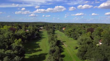Schlachtensee gölleri, güneşli bir günde, masmavi gökyüzü ve bulutlarla çevrili yemyeşil ormanlarla çevrilidir. İticileri ileri çalıştır 