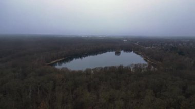 Göle bakan, ağaçlarla çevrili ve Almanya 'da bulutlu bir gökyüzünü yansıtan insansız hava aracı. uçuş üstü insansız hava aracı 