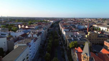 Berlin 'in yerleşim bölgesinden geçen sarı yükseltilmiş tren. Ters İHA uçuşu 