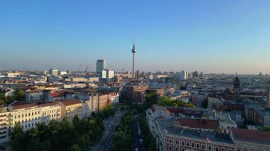 Berlin TV kulesi çatıların üstünde yükseliyor ve gün batımında Senefelderplatz 'da bir inşaat sahası var. Ters İHA uçuşu 