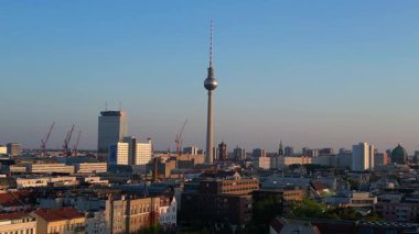 Berlin TV kulesi şehrin üzerinde dikiliyor, altın saatin sıcacık parıltısıyla yıkanıyor. İHA alçalıyor 