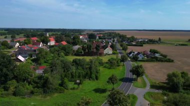 Almanya 'nın Brandenburg kentinde güneşli bir yaz gününde geniş tarım sahalarının ortasına kurulmuş küçük bir köy olan Tarmow' un Idyllic manzarası. Ters İHA uçuşu 