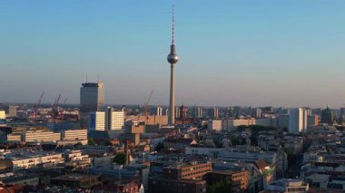 Berlin TV kulesi şehrin üzerinde dikiliyor, altın saatin sıcacık parıltısıyla yıkanıyor. panorama genel görünüm dronu 