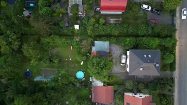 Brandenburg, Almanya 'da sakin bir akşam, çatıların, yemyeşil otlakların ve bir yol ağının sergilendiği bir yerleşim alanına iniyor. dikey kuş bakışı dron 