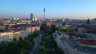 Berlin TV kulesi çatıların üstünde yükseliyor ve gün batımında Senefelderplatz 'da bir inşaat sahası var. Dolly sol İHA 