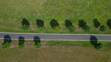 Kırsal bir yolda mavi gökyüzünün altındaki geniş tarlalardan geçen arabaların hava görüntüsü. Yukarıdan insansız hava aracı görüntüleri 