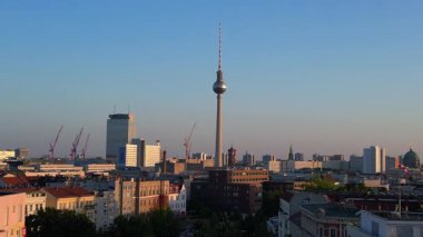 Berlin TV kulesi şehrin üzerinde dikiliyor, altın saatin sıcacık parıltısıyla yıkanıyor. İHA yükseliyor 