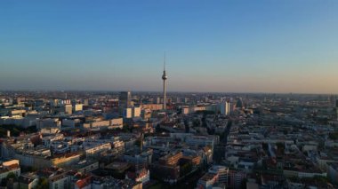 Berlin TV kulesi şehrin üzerinde dikiliyor, altın saatin sıcacık parıltısıyla yıkanıyor. panorama genel görünüm dronu 