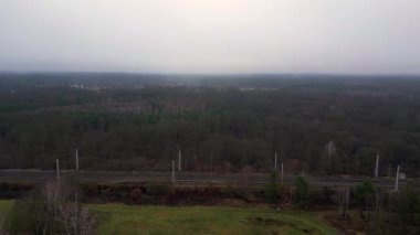 Demiryolu manzarası bulutlu gökyüzü altındaki büyük ormanı geçerek karamsar ve atmosferik manzaralar yaratıyor. uçuş üstü insansız hava aracı 